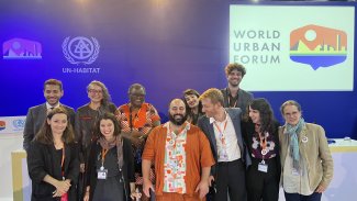 11 people smiling and standing in front of a panel at an event at the World Urban Forum